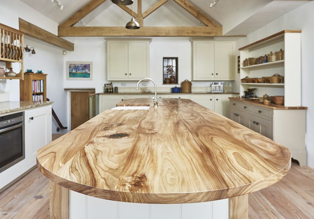 A long kitchen island with natural wood top and built in sink